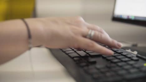 a young attractive woman is typing on a keyboard in her room, close-up on her fingers