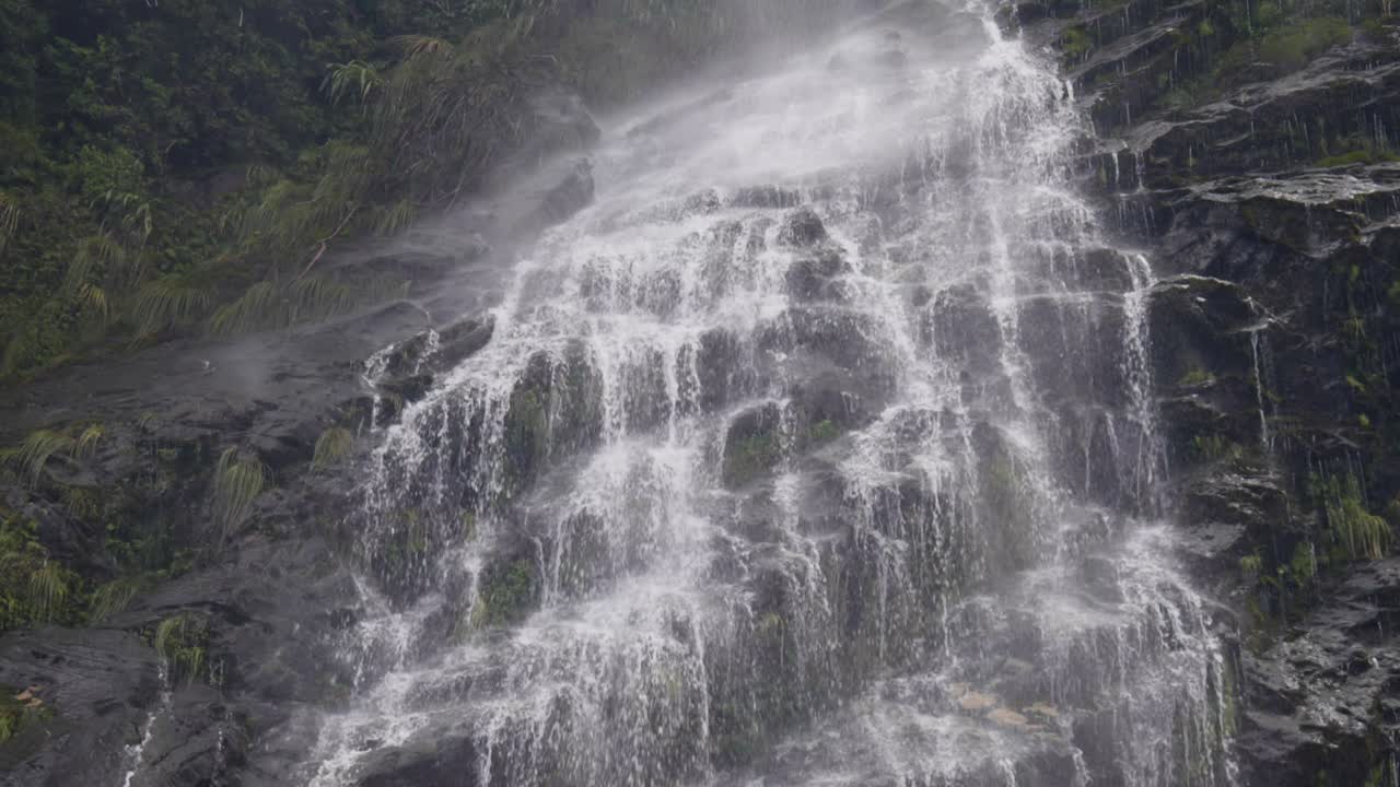 Vista a cámara lenta del agua goteando suavemente por un acantilado rocoso, que revela un movimiento delicado, la textura y una atmósfera natural tranquila y meditativa.
