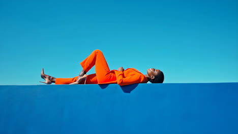 stylish woman in orange suit against blue background