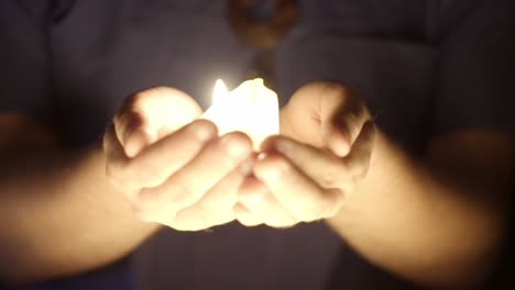 vista de cerca de la luz de las velas brillando en las manos
