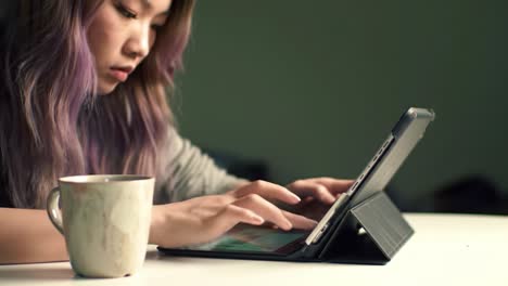 a young woman engaged in digital creativity on a tablet while enjoying a warm beverage in a calm and trendy environment