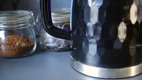 a man switching on an electric kettle in a kitchen at home close up