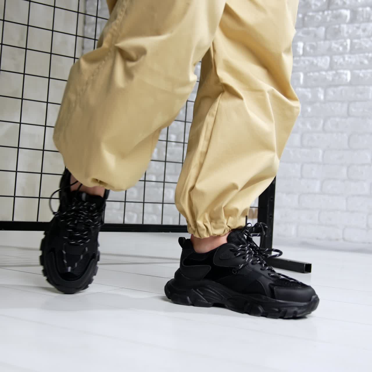 Sports wear and footwear demonstration in the photo studio. Black leather modern sneakers close up