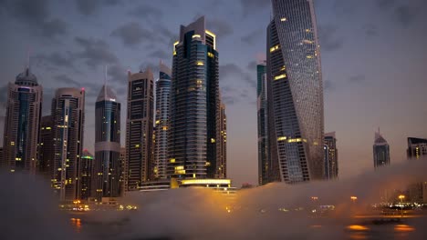 illuminated skyscrapers of dubai marina rise dramatically from a dense layer of low clouds at dusk, forming a striking and futuristic cityscape that captivates with its urban elegance