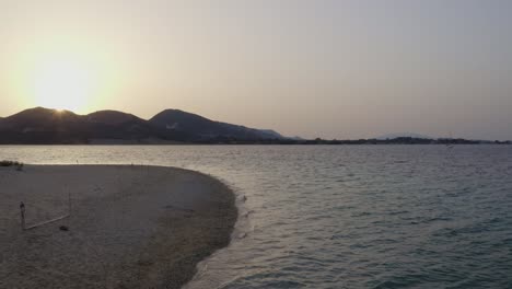 Aerial---Low-slow-pass-over-Marathonis,-Zakynthos,-Greece-at-sunset