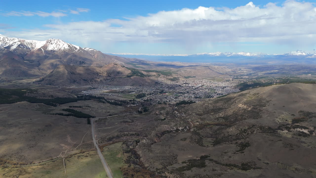 Slider drone shot over Esquel town, south Argentina. Dry hills make contrast with snow in mountain range and background. 4K-60fps.