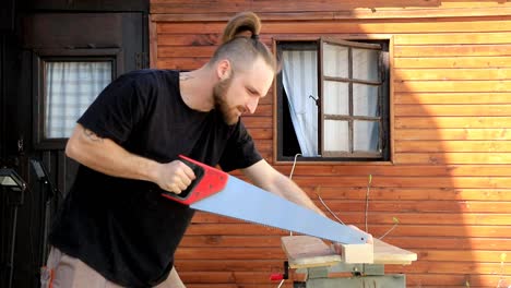 man sawing wood with hand saw