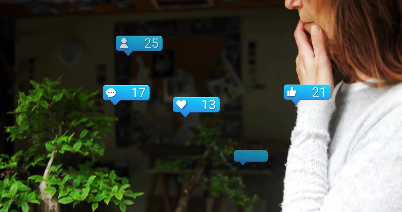 woman standing holding chin in home office, interacting with floating social media icons and bonsai