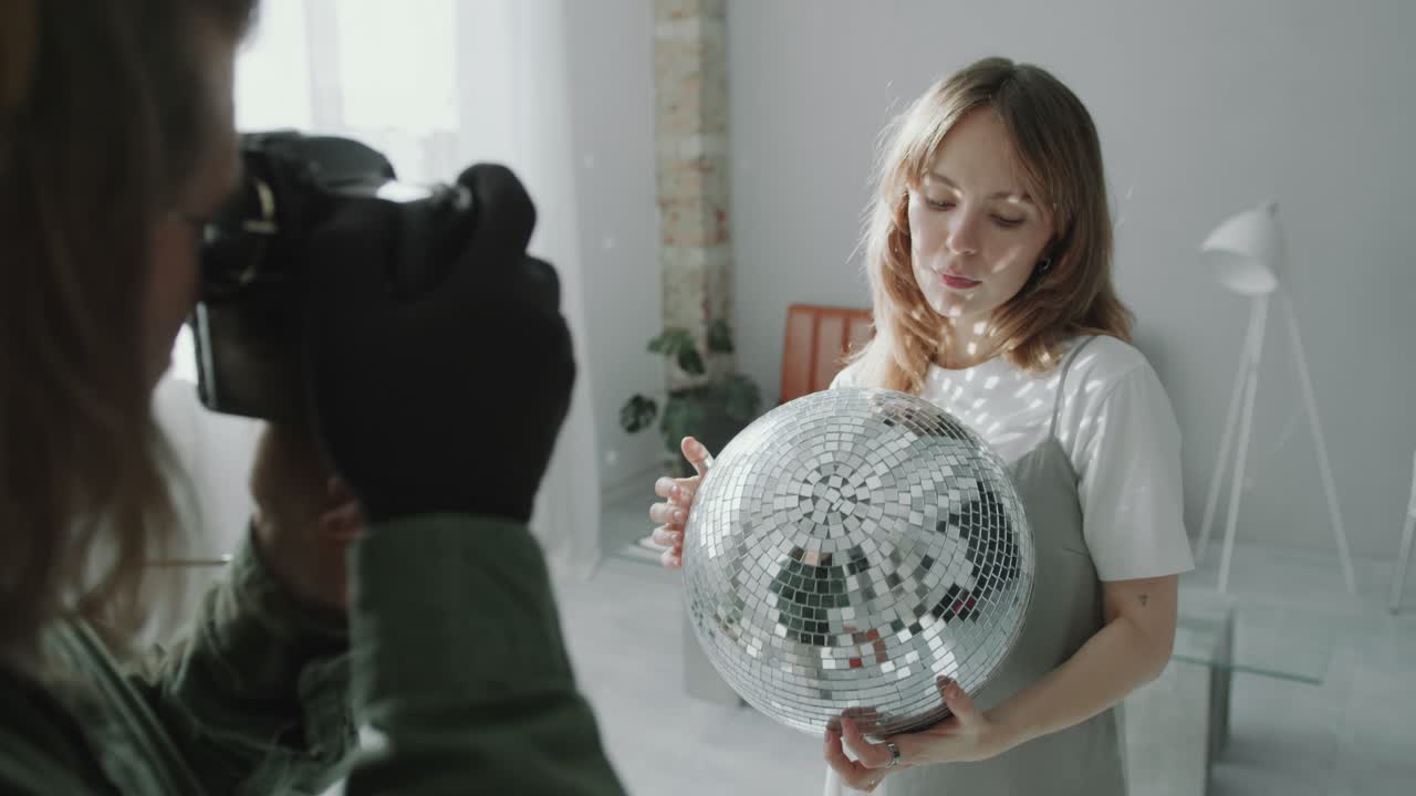 Pretty Woman Posing with Disco Ball during Photo Shoot in Studio