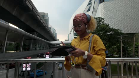 young woman using tablet on a city overpass