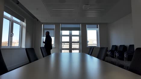 silhouette of a businessman pacing up and down in a meeting room, holding a smartphone