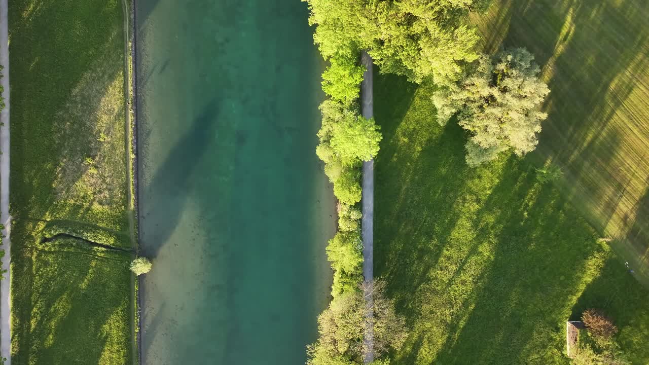 은 날, 강에서 푸른 풀과 식물 나무로 둘러싸인 깨한 도로의 위쪽의 새의 시야