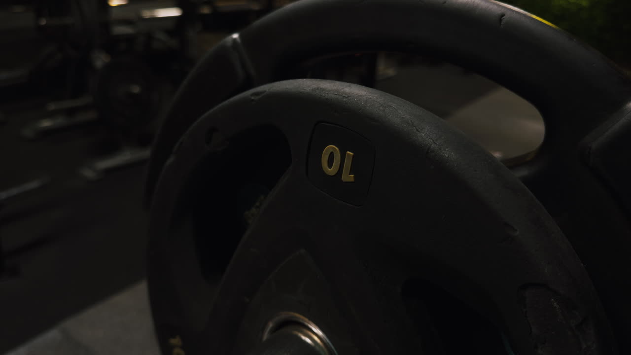 Close up of person placing 10 kilogram weight plate on gym machine. Strength training, fitness workout and muscle building concept