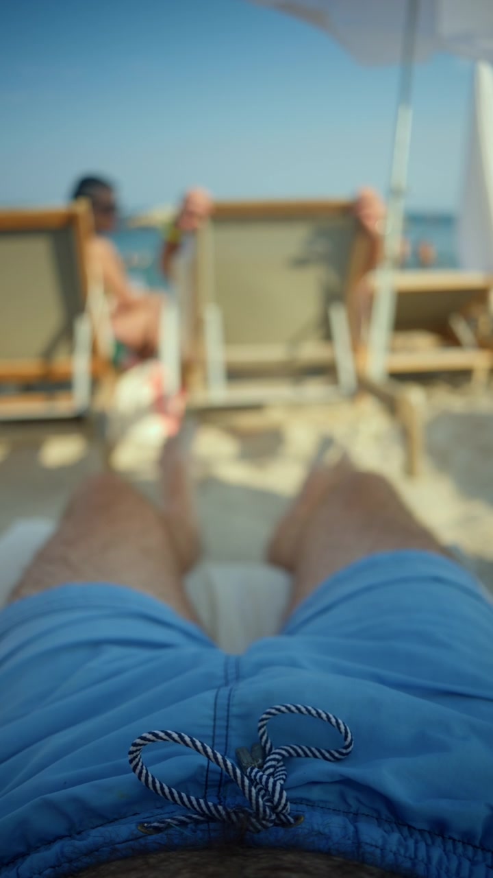 Man in blue swim trunks relaxing on a beach lounger under the summer sun, enjoying vacation and leisure time