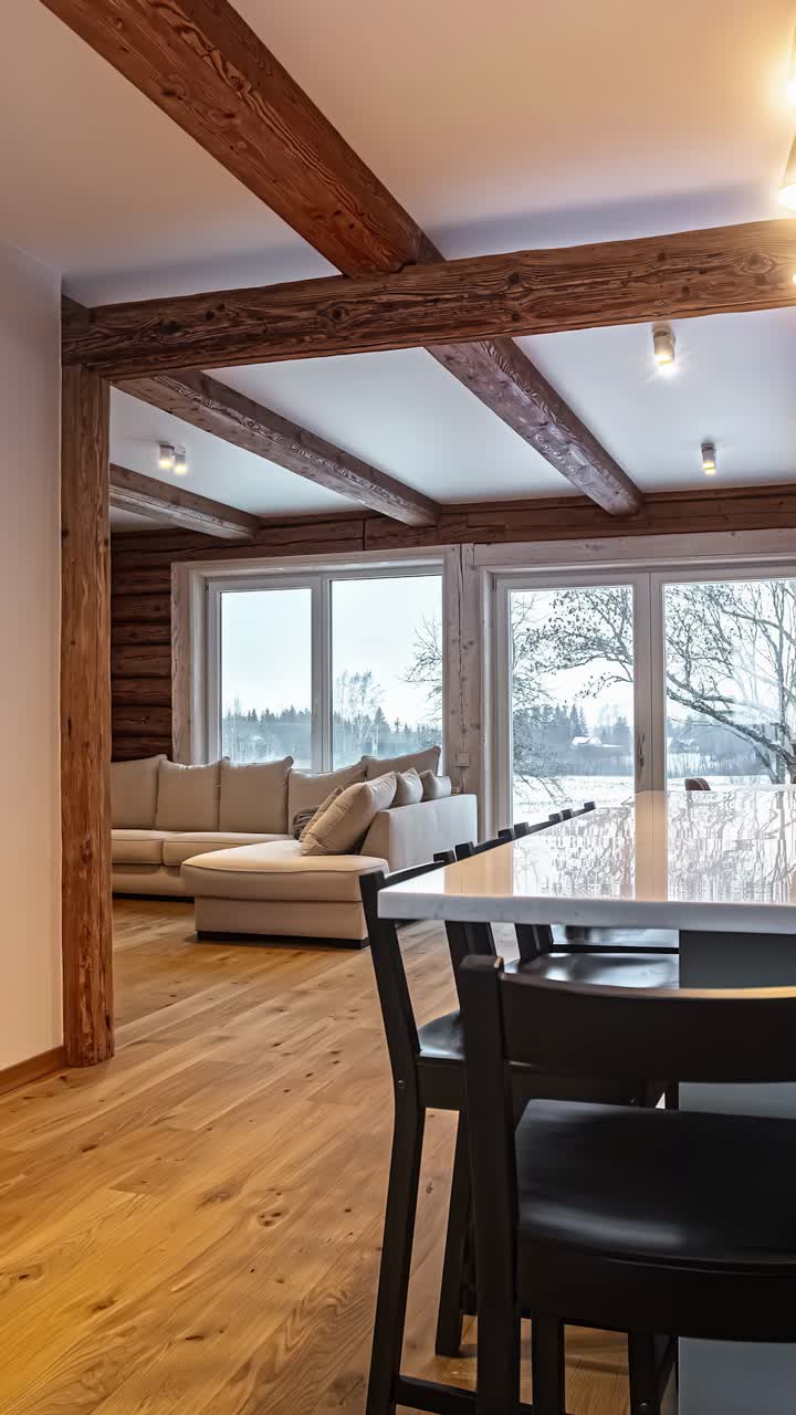 A Rustic-Modern Cabin Interior with a Cozy Living Area, Sleek Dining Space, and Open Kitchen, all Framed by Wood Beams and Large Scenic Windows - Vertical Shot