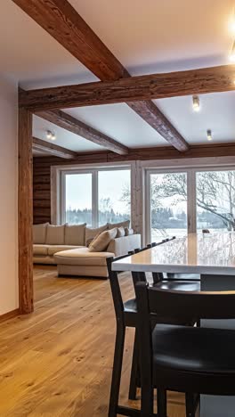 a rustic-modern cabin interior with a cozy living area, sleek dining space, and open kitchen, all framed by wood beams and large scenic windows - vertical shot