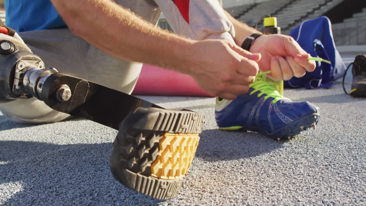 sección baja de un atleta masculino caucásico discapacitado sentado, atando un zapato
