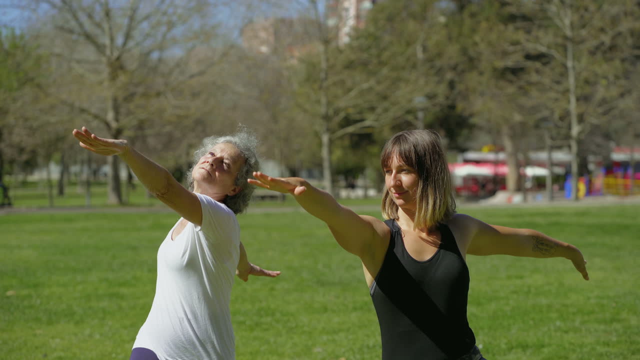 Due donne che praticano yoga in un parco estivo soleggiato