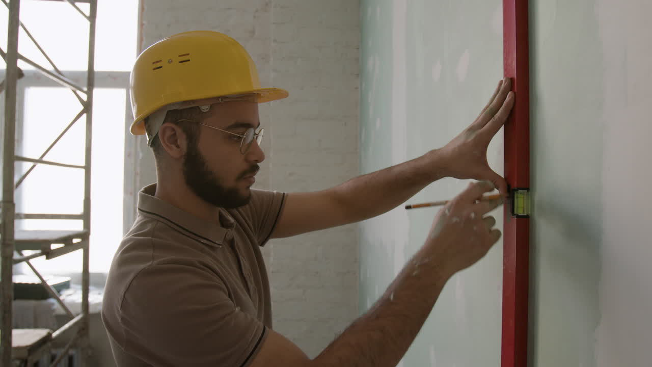 Construction worker using level on wall