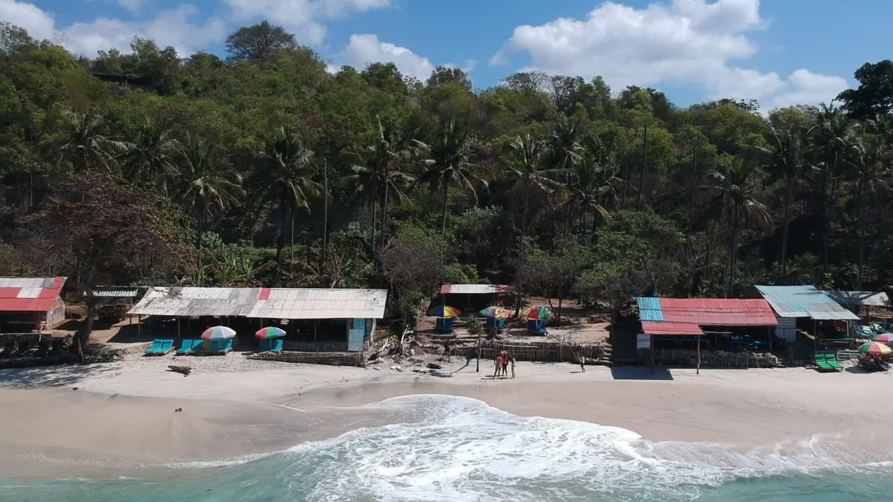 panoramic drone shot of the small secret beach, with hut and palm tree jungle on the background padang bai in Bali, Indonesia