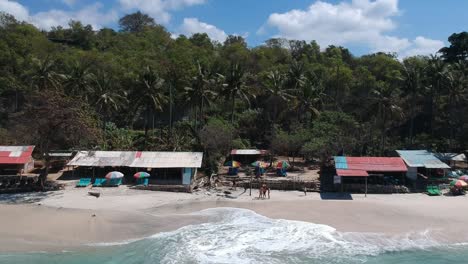 panoramic drone shot of the small secret beach, with hut and palm tree jungle on the background padang bai in bali, indonesia