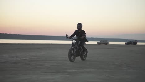 Side-view-of-unrecognizable-biker-in-helmet-and-jacket,-man-is-riding-at-sport-motorbike-in-evening,-pink-dusk