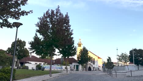 daytime scene of empty street with view, park walking area with trees on one side and religious church building visible