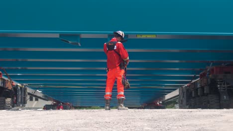 construction worker in orange gear inspects bridge rigging under a steel structure in south france