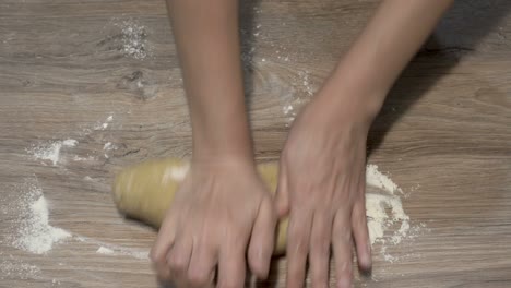 una mujer amasa un pedazo de masa cruda con las manos para hornear en una cocina doméstica, en la mesa. la vista desde arriba. de cerca. sin rostro. 4k.