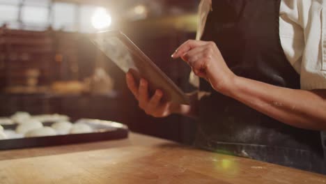 Animation-of-hands-of-asian-female-baker-using-tablet