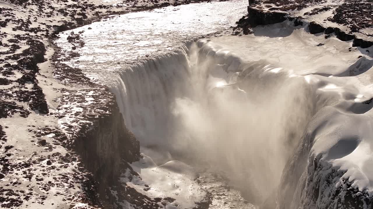 Mighty waterfall cascading in the wilderness, surrounded by snow and rugged terrain
