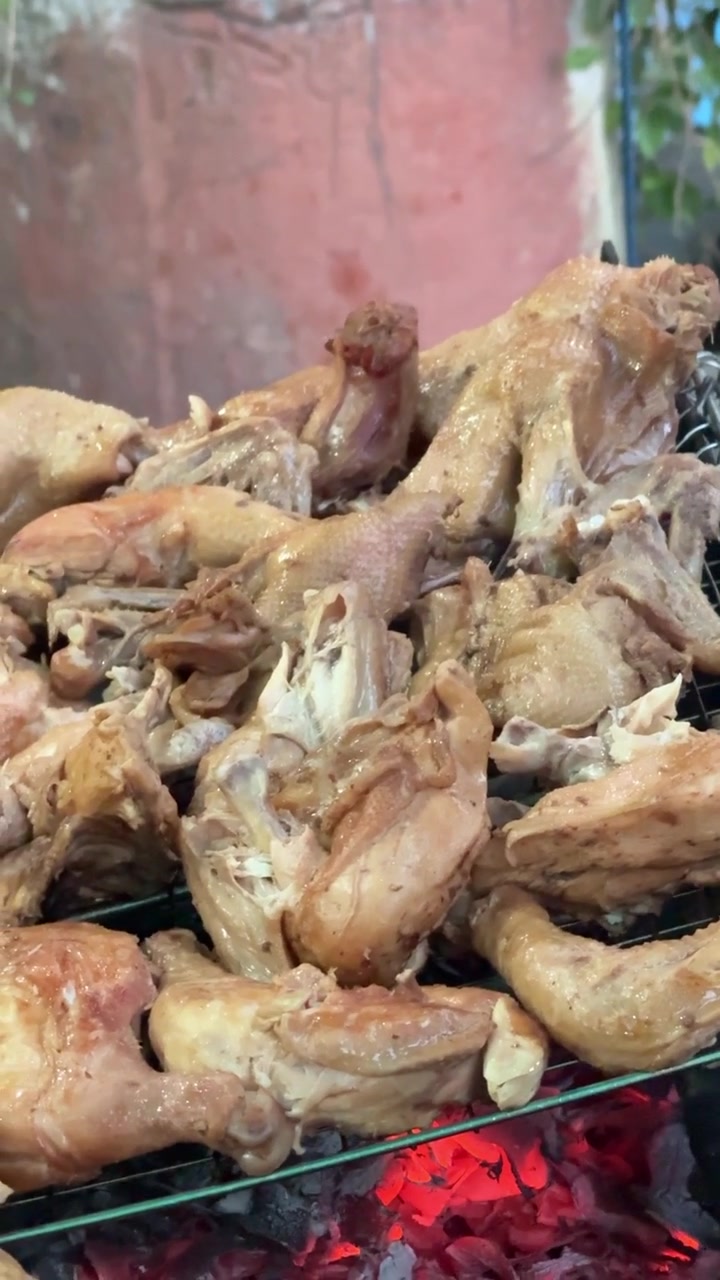 Pezzi di pollo che grigliano su braci ardenti.
