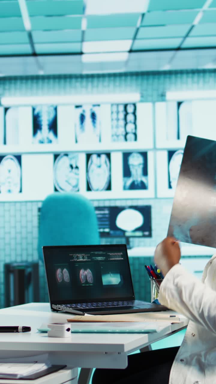 Professionisti medici che discutono radiografie e referti diagnostici del paziente su un laptop.