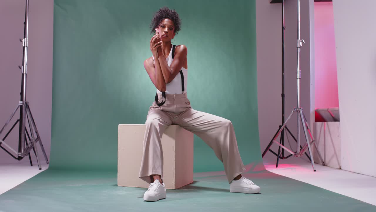Young Woman Posing Confidently on a Cube in a Photo Studio