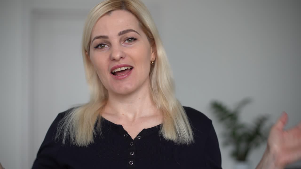 Giovane donna felice fa una videochiamata, chiacchiera e ride, godendosi una conversazione online e guardando la webcam. Ragazza allegra, blogger e influencer, parla alla telecamera registrando un vlog per il suo canale.