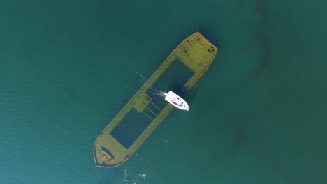 cenital aerial view of a boat driving over a shipwreck on lake saimaa, finland