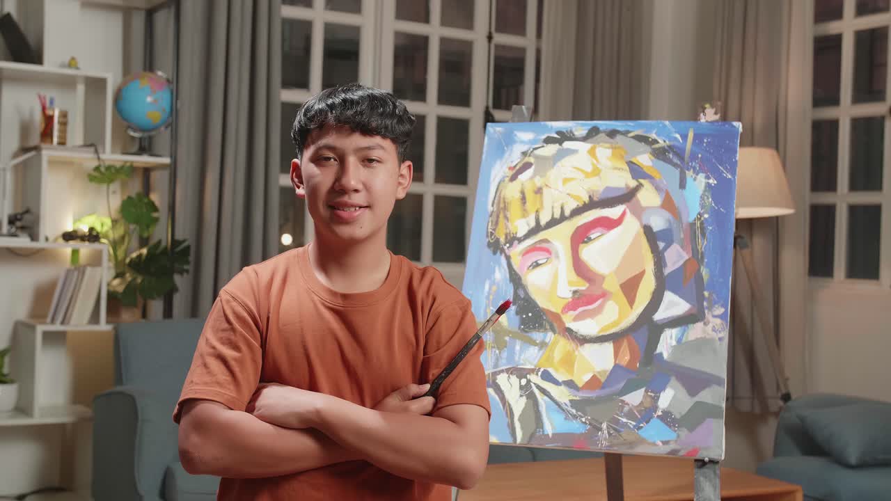 Asian Artist Boy Holding Paintbrush Mixed Colour, Crossing His Arm, And Smiling After Finish Painting A Girl On The Canvas
