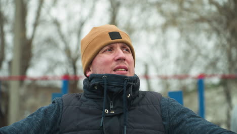 a coach seated on workout equipment appears contemplative, in the background, two boys play football