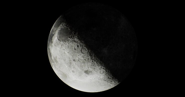 Lua crescente iluminada em um céu noturno escuro com crateras visíveis
