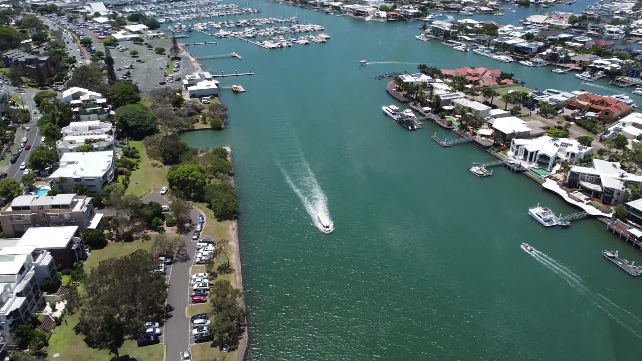 4K drone footage of a boat harbour with boats passing by and high end private homes near by