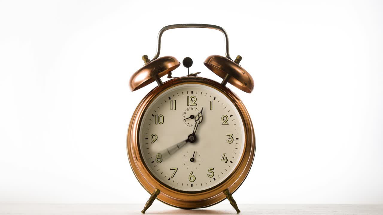 시계 손이 빠르게 회전하는 시간 지연. 시계 손은  바탕에 빈티지 청동 알람 시계에 빠르게 회전합니다.