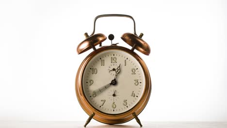 la aguja del reloj gira rápidamente el lapso de tiempo. la aguja el reloj gira rápido en el reloj de alarma de bronce vintage sobre fondo blanco.