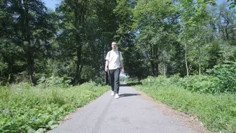 young man walking with guitar on street near forest