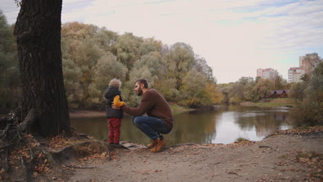 descanso familiar en el bosque de otoño el padre está hablando con el hijo del niño y mostrando el pintoresco lago en el bosque senderismo en la naturaleza en el fin de semana de otoño