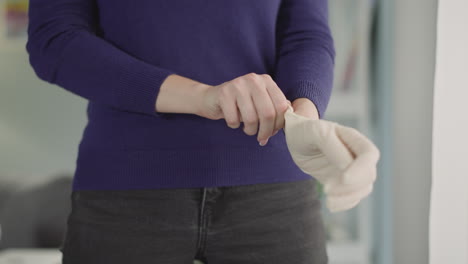 Woman-puts-sterile-glove-on-hand-preparing-for-procedure