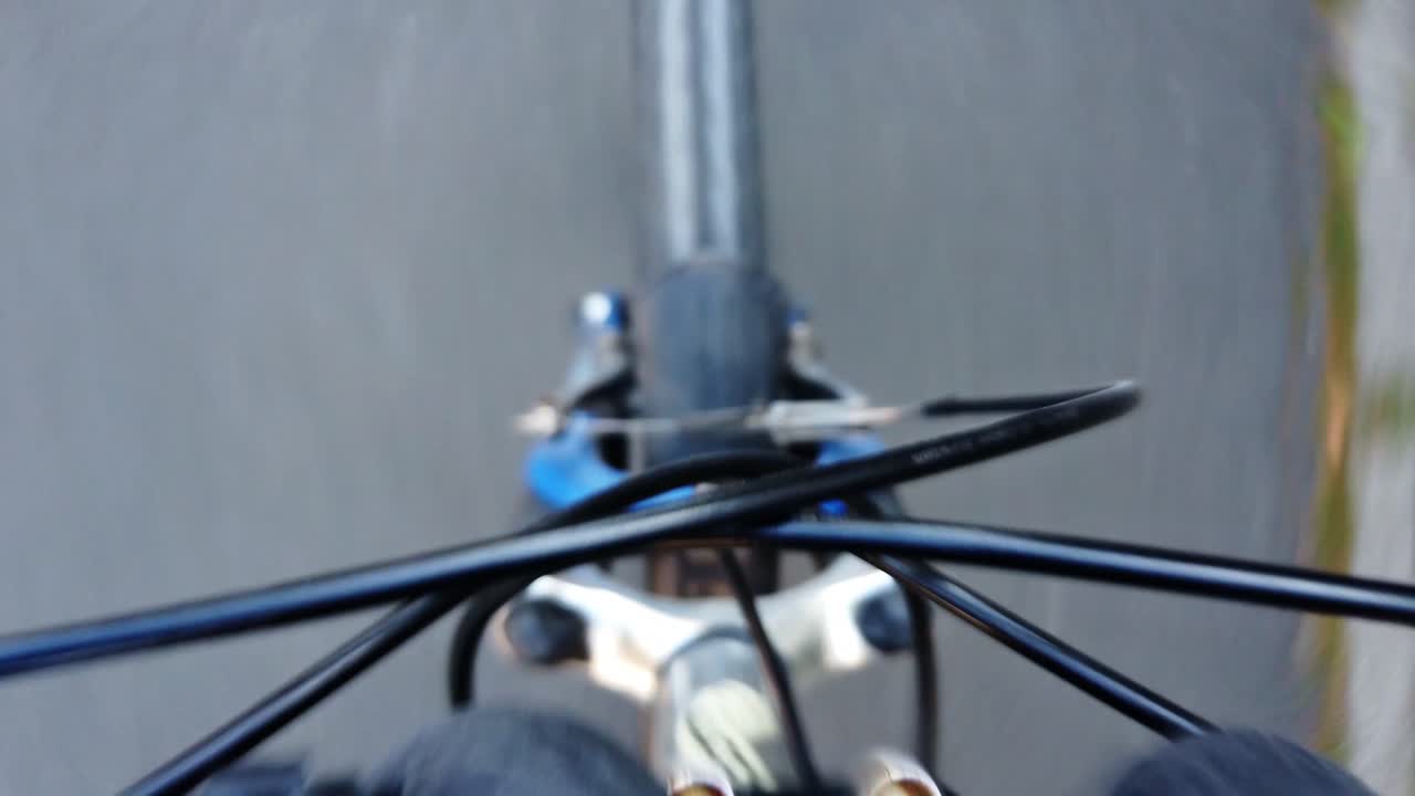 point of view pointing down on a bumpy bikeride, showing the front tire, the bike is making turns and the ground is changing ist composition