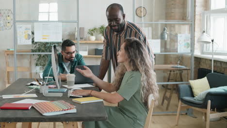 african american man and caucasian woman discussing project on computer in office