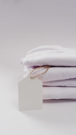 vertical video of stack of folded white t shirts with copy space on white background