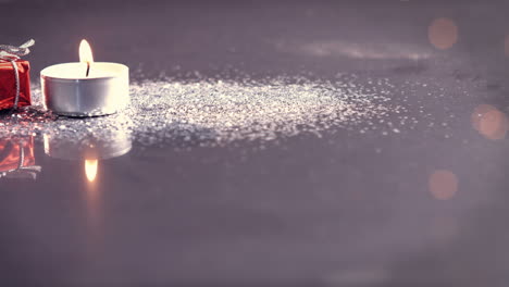 view of candle burning next to little christmas present