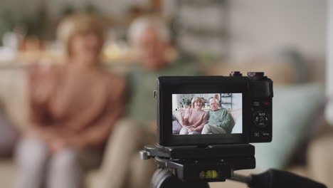 digital camera filming positive elderly couple at home